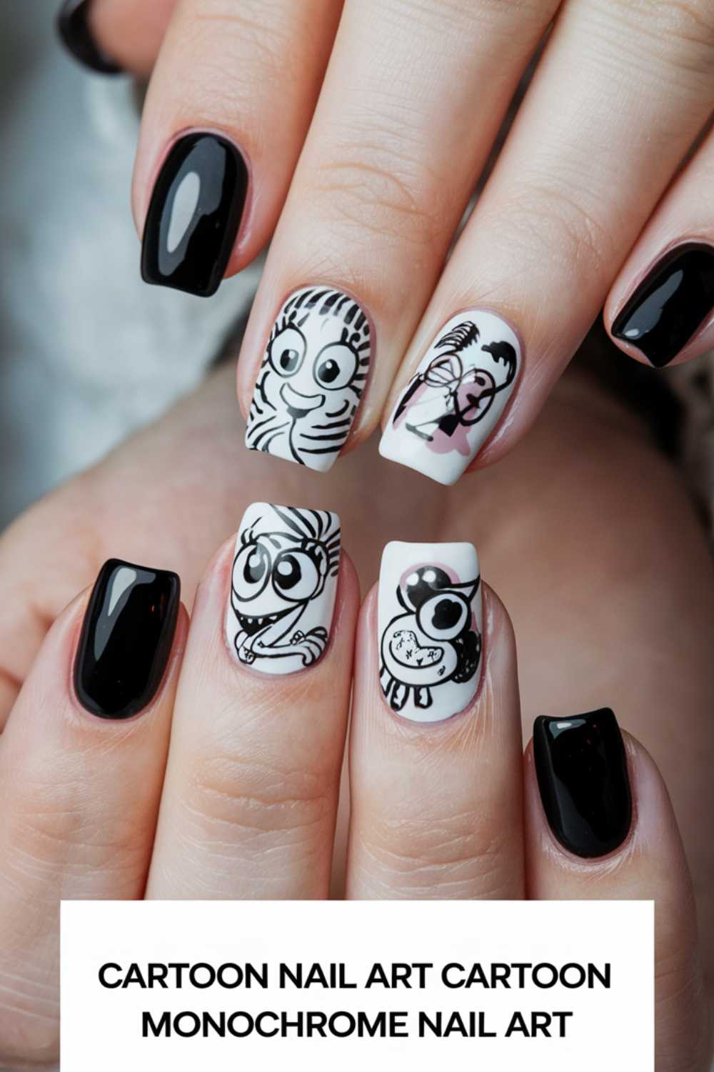 Fingers with cartoon nail art designs showcase black and white themes. Two nails flaunt zebra faces; one highlights a flamingo, while another displays a wide-eyed character clutching a heart. The remaining nails are painted in plain black for a bold contrast.