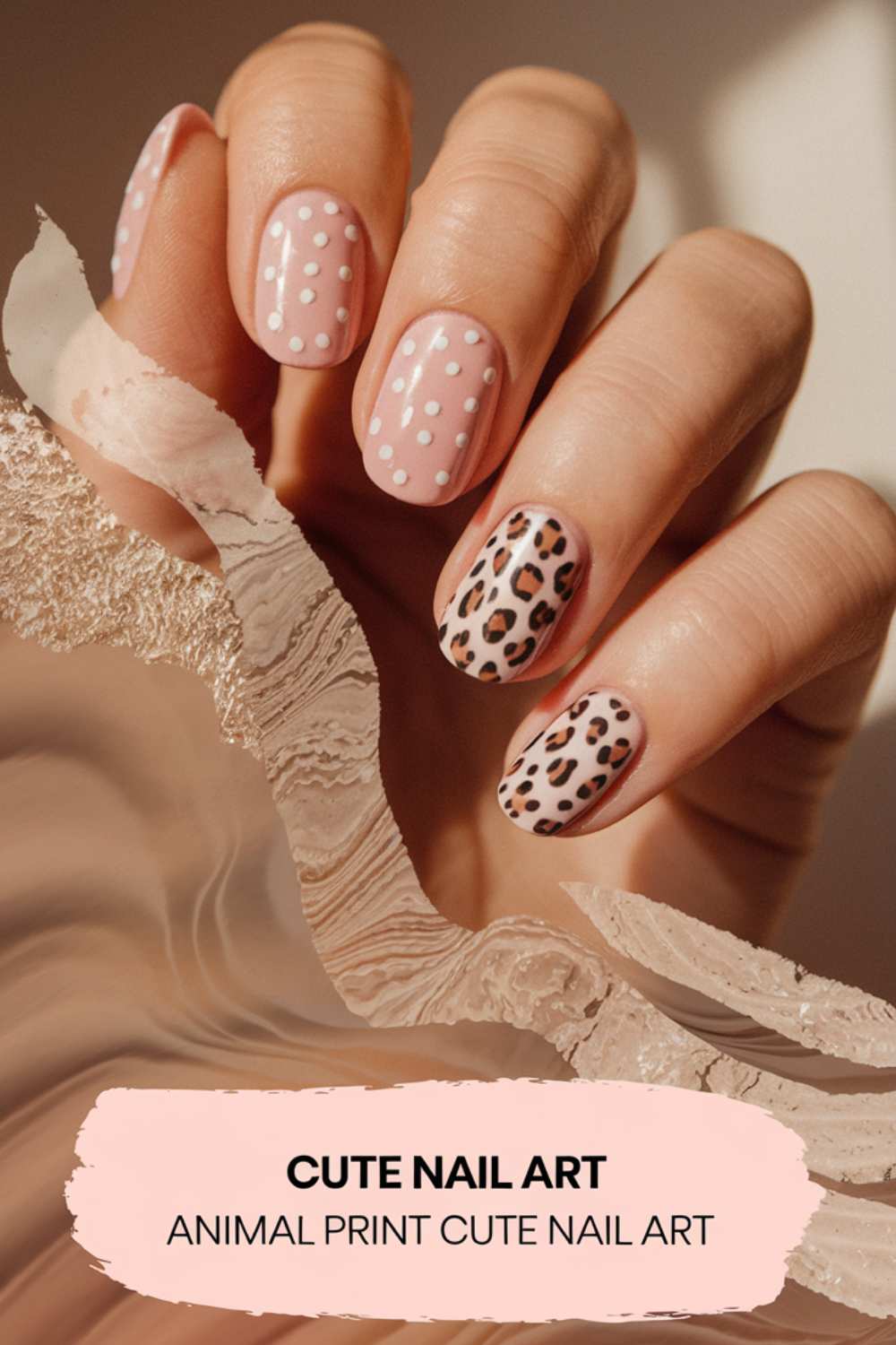 A hand showcases cute nail art: two nails flaunt pink polish with white polka dots, while the other two display a striking leopard print. The marbled swirl background enhances the charm. Text at the bottom reads: Cute Nail Art - Animal Print.