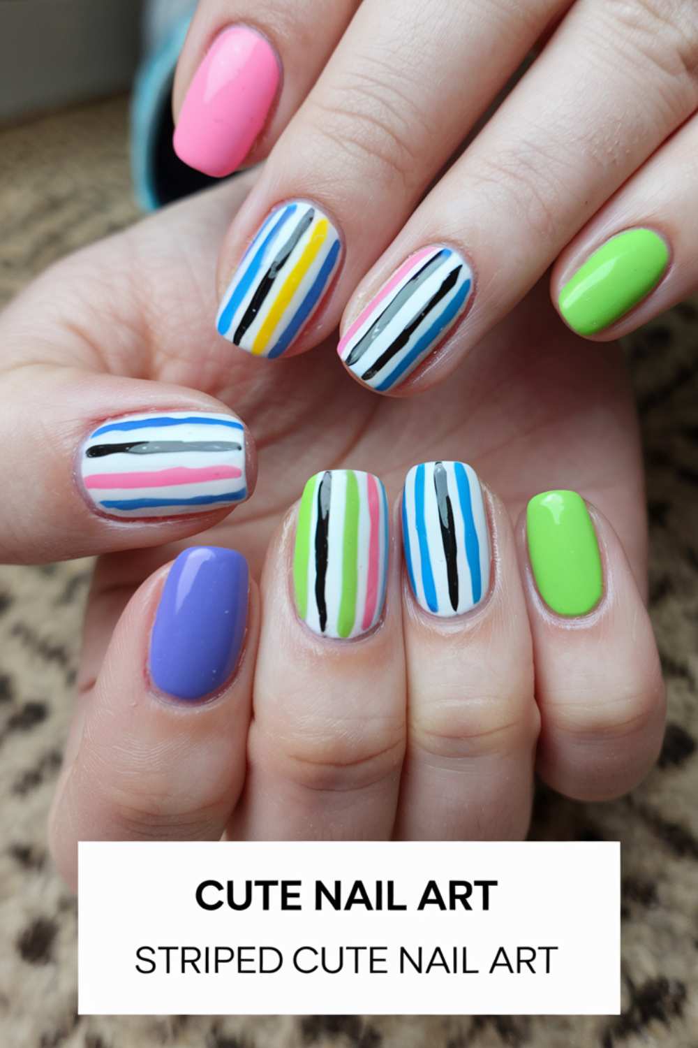 Close-up of hands showcasing cute nail art. Each nail glows with vibrant colors like pink, blue, green, and white, adorned with vertical stripes in playful combinations. Text overlay reads, CUTE NAIL ART: STRIPED CUTE NAIL ART.