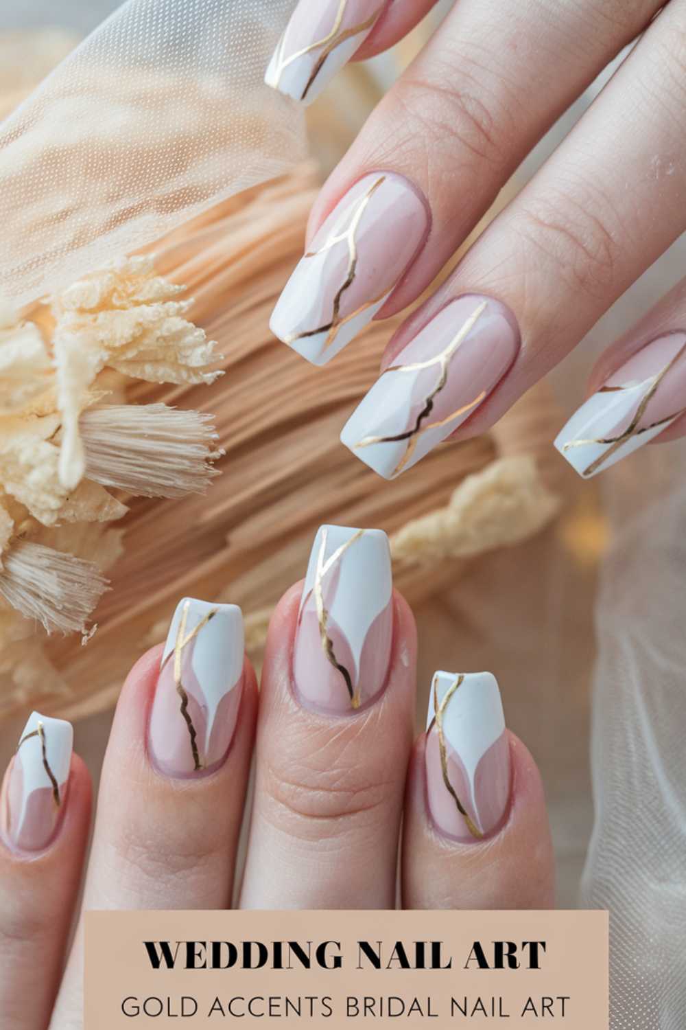 Close-up of hands with wedding nail art. Nails feature gold accents on white and pink marble-like patterns. A soft-focus background includes beige dried flowers. Text reads: Wedding Nail Art: Gold Accents Bridal Nail Art.