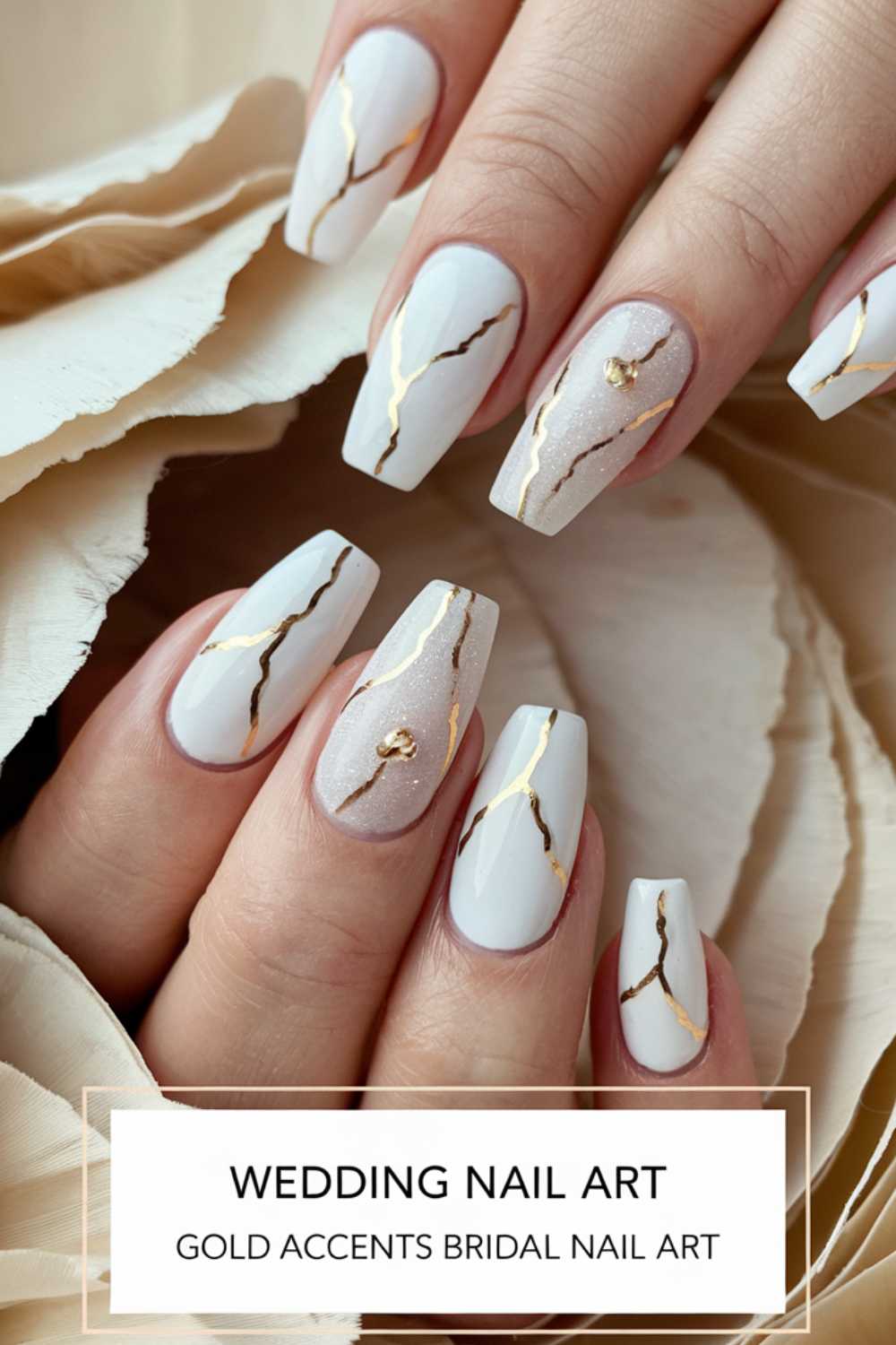 Close-up of hands with long, white nails featuring gold cracks and accents, styled in an elegant bridal nail art design. Text overlay reads, Wedding Nail Art - Gold Accents Bridal Nail Art.