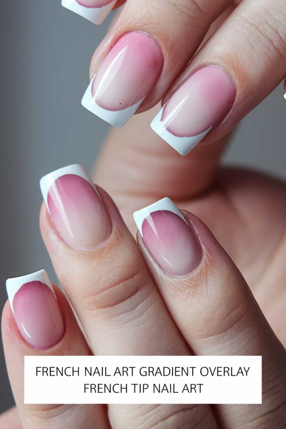 Close-up of a hand with nails featuring a French tip design. The nails have a gradient overlay, blending from pale pink near the cuticle to white at the tips. The text reads: French Nail Art Gradient Overlay French Tip Nail Art.