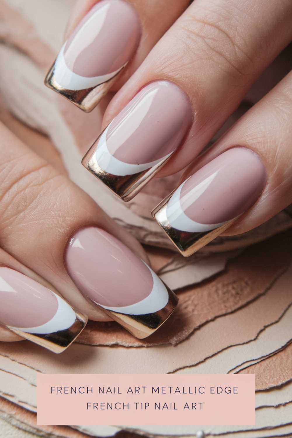 Close-up of a hand with a French manicure featuring metallic rose gold tips and a white edge. The nails have a soft nude base. Text at the bottom reads, French Nail Art Metallic Edge French Tip Nail Art.