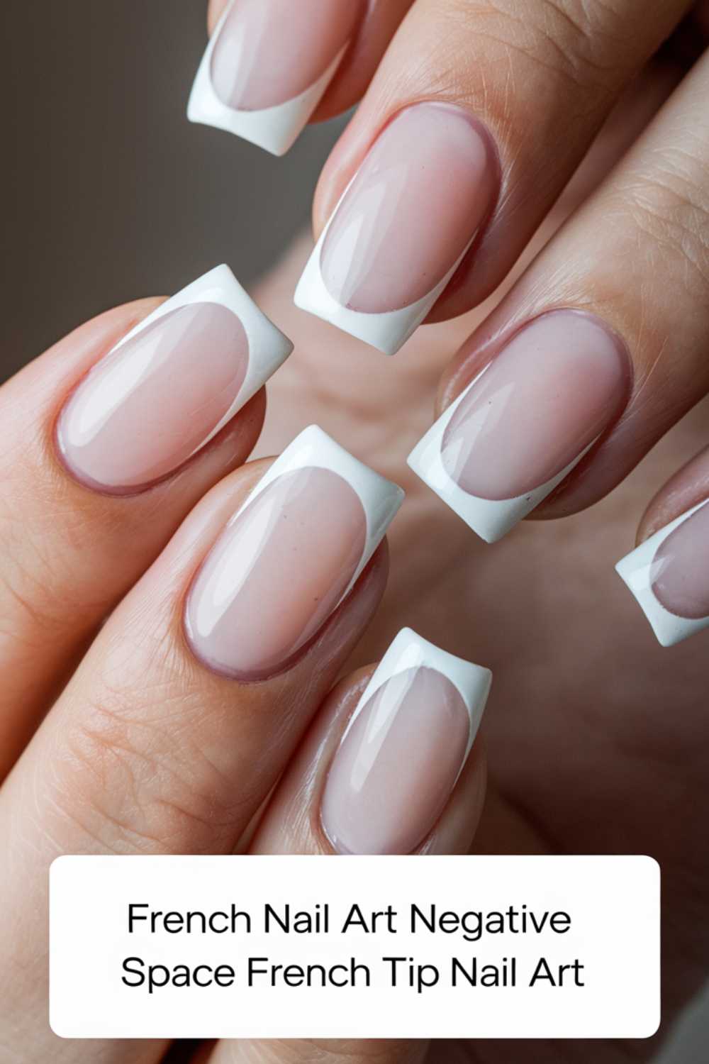 Close-up of hands featuring a French manicure with negative space nail art. The nails have a clear base and white tips, creating an elegant and minimalist look.