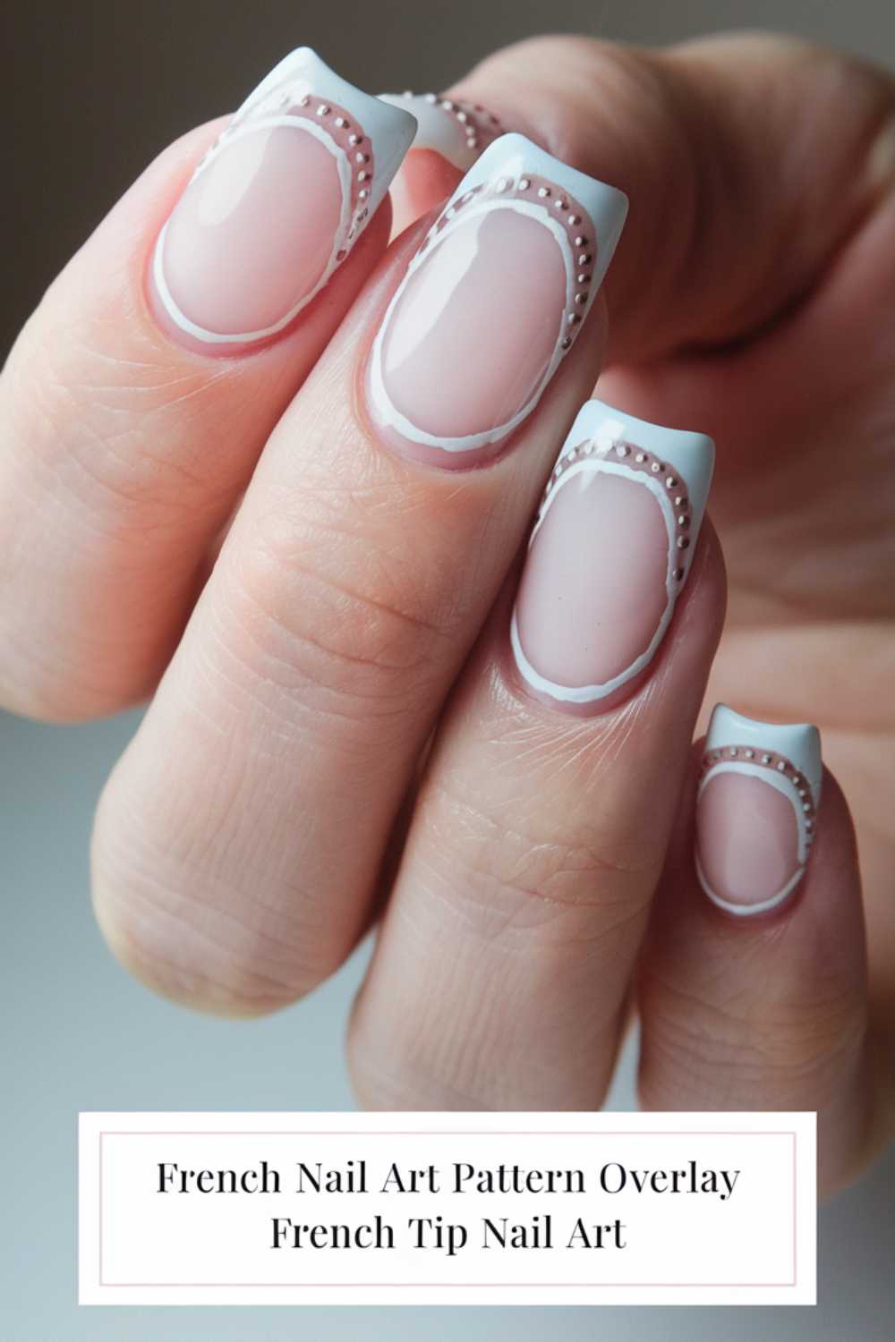 Close-up of a hand with stylish French tip nails. The nails feature a pink and white ombre base with delicate white and pink bead-like patterns near the cuticle. Text at the bottom says French Nail Art Pattern Overlay French Tip Nail Art.