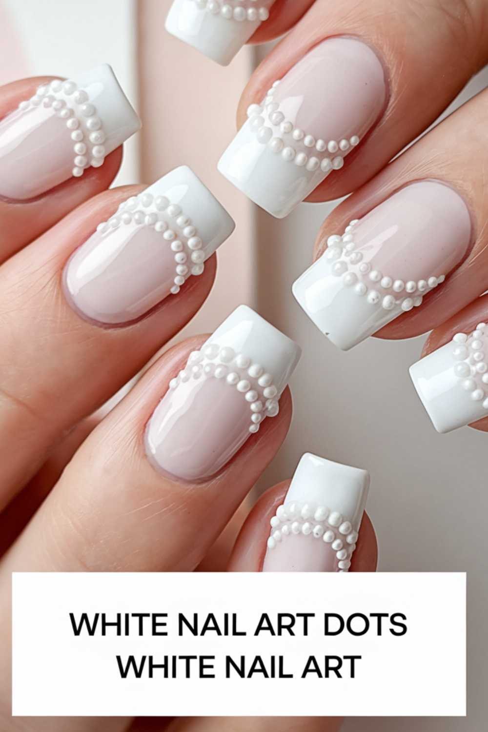Close-up of hands with French manicure featuring white tips adorned with dotted pearl-like decorations. The nails have a glossy finish. Text on the image reads: WHITE NAIL ART DOTS WHITE NAIL ART.