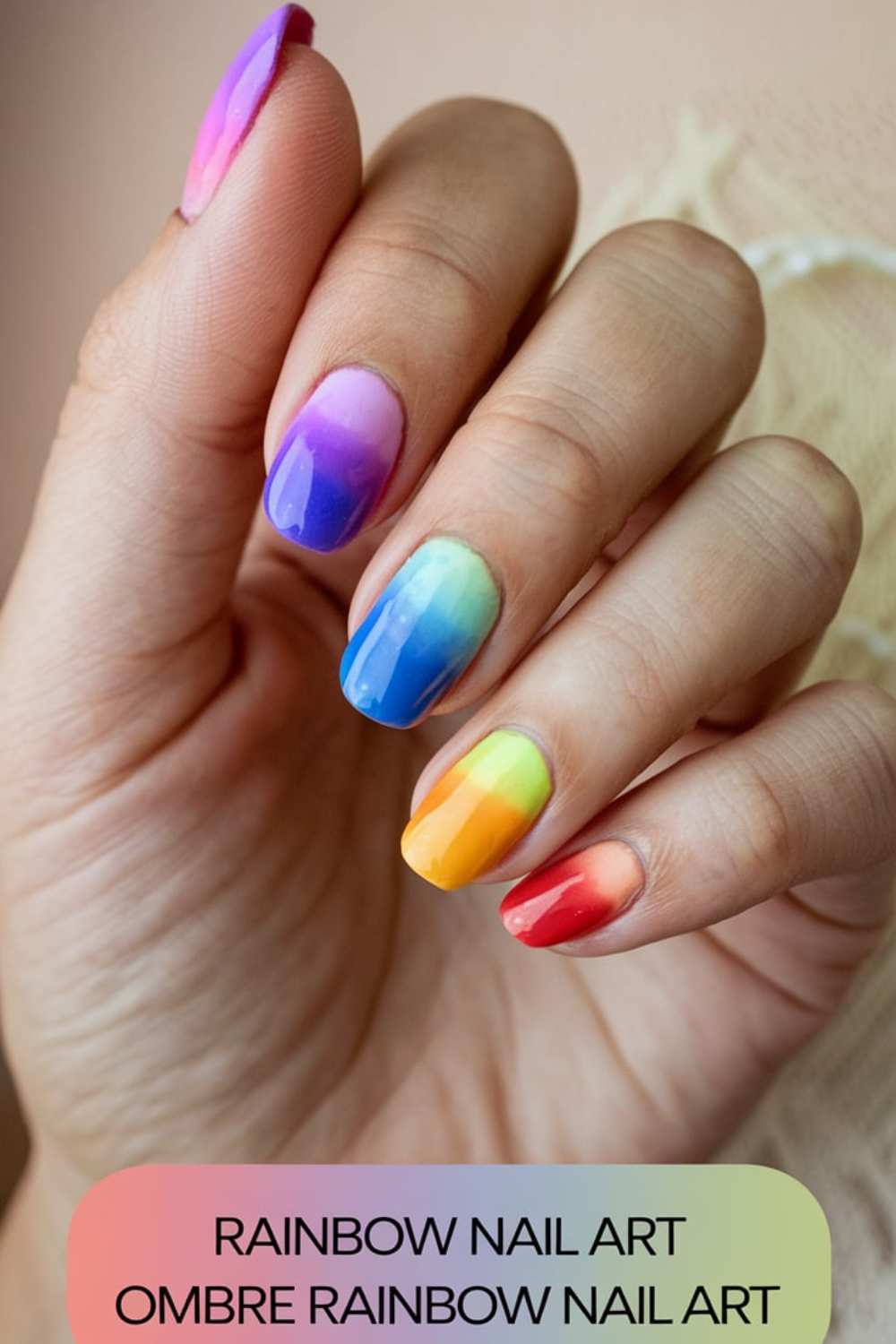 A hand showcases stunning rainbow ombre nail art, with each nail transitioning seamlessly through shades of purple, blue, green, yellow, and red. Below is the text RAINBOW NAIL ART OMBRE RAINBOW NAIL ART, epitomizing the vibrant beauty of Rainbow Nail Art.