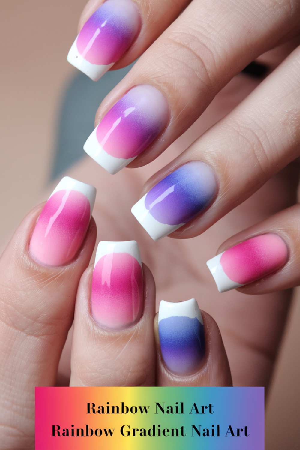 Close-up of hands with nails featuring a stunning rainbow nail art design, transitioning from pink to purple, with tips finished in smooth white. A vibrant text at the bottom reads, Rainbow Gradient Nail Art.