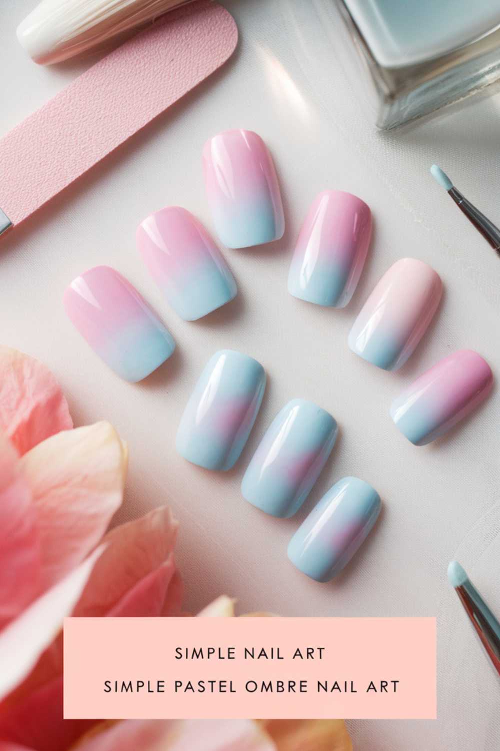 A set of pastel ombre press-on nails, elegantly transitioning from pink to blue, is displayed on a table. Beside them lie a pink nail file and a brush. Below, the words SIMPLE NAIL ART capture the essence of this soothing pastel ombre creation.
