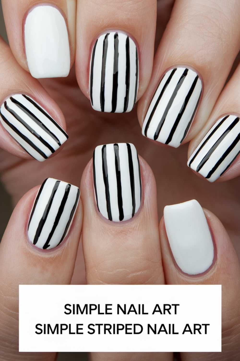 Close-up of hands displaying white nails adorned with black vertical stripes, while one nail remains solid white. At the bottom, the text reads: Simple Nail Art, Simple Striped Nail Art.