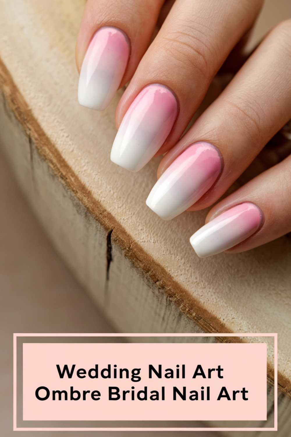 Close-up of a hand with long, oval-shaped nails featuring an ombre design blending pink and white. The background is a light wooden texture. Text at the bottom reads, Wedding Nail Art Ombre Bridal Nail Art.