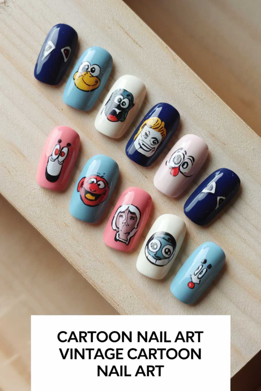 A set of false nails showcasing cartoon nail art designs with vintage characters. Each nail is painted with a unique character on pastel and dark backgrounds, elegantly displayed on a wooden surface.