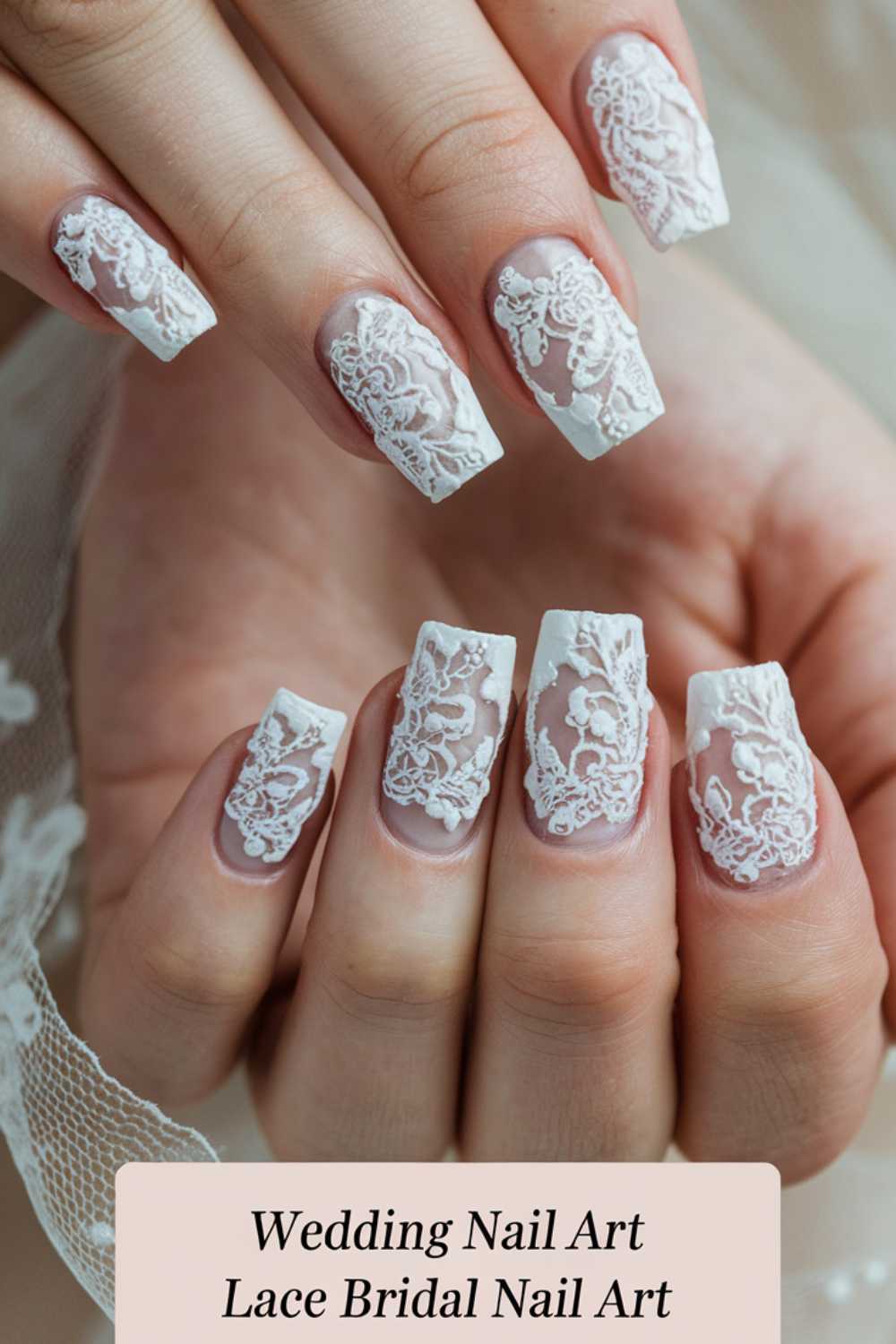 Close-up of a hand showcasing square-shaped nails with intricate white lace designs over a nude base. The nails have a delicate, bridal appearance. Text reads, Wedding Nail Art Lace Bridal Nail Art.