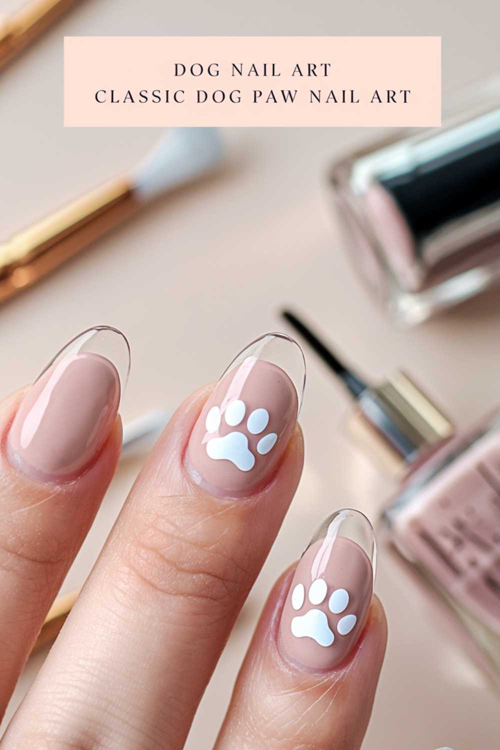 A close-up showcases fingers with clear tips and nude nail polish, adorned with delicate white dog paw print designs. Blurred in the background are nail care tools and a bottle of pinkish nail polish. Text reads, Dog Nail Art Classic Dog Paw Nail Art.