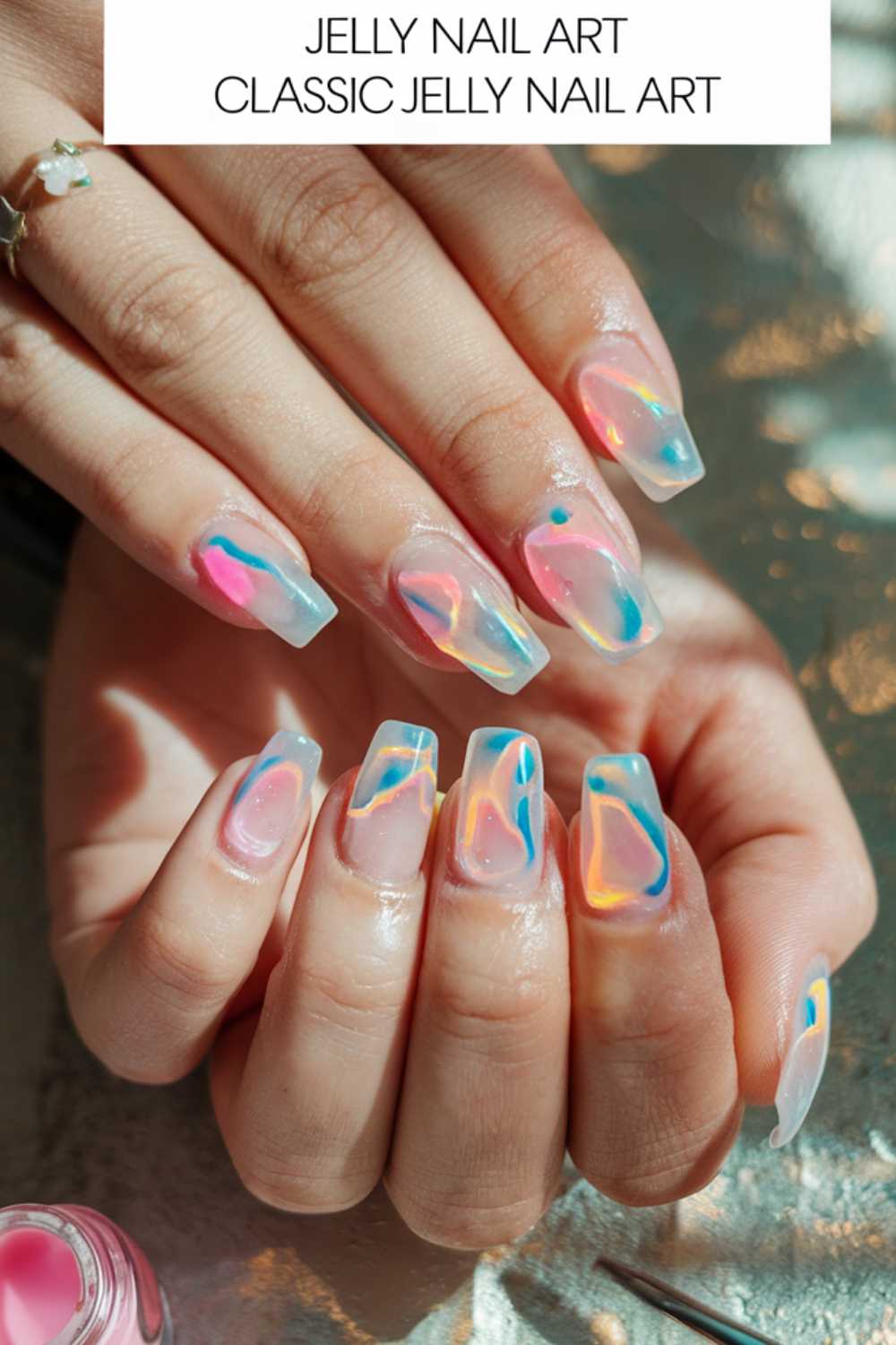 A person showcases hands adorned with colorful jelly nail art ideas featuring clear bases and vibrant pastel swirls in blue, pink, and orange. The nails boast a glossy finish, delivering a translucent effect. Text at the top reads Jelly Nail Art Classic.