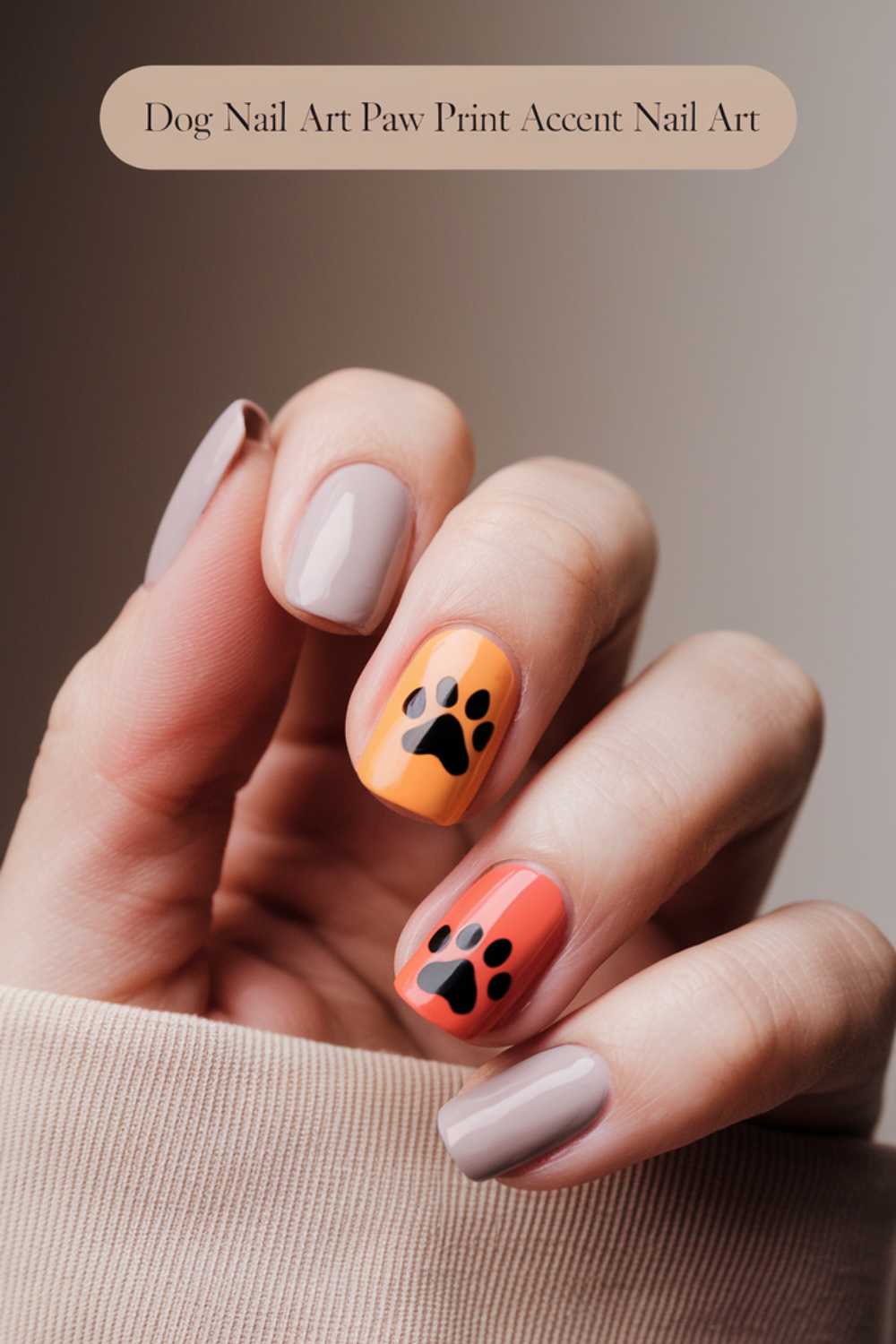 A hand with manicured nails showcases a delightful Dog Nail Art design. Most nails feature light pink polish, while two boast vibrant orange and coral backgrounds adorned with black dog paw prints. The thumb partially reveals light pink polish. Text at the top reads, Dog Nail Art Paw Print Accent Nail Art.