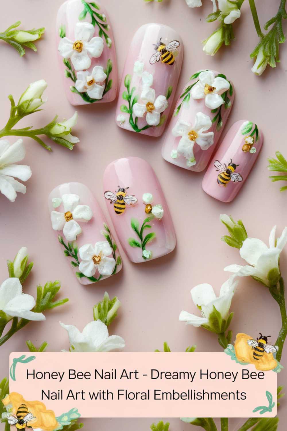 Pink nails with white floral designs and 3D bee embellishments create a delightful look. Surrounded by small, white flowers, this dreamy Bee Nail Art captures the essence of nature. Text overlay reads: Honey Bee Nail Art - Dreamy Honey Bee Nail Art with Floral Embellishments.