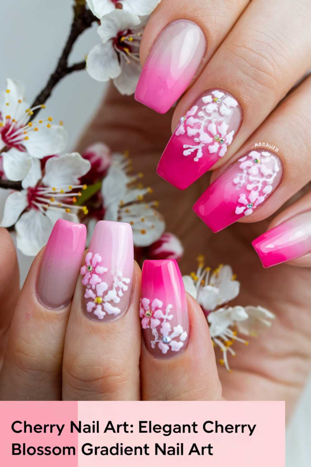 Close-up of a hand showcasing stunning cherry blossom-themed nail art. The gradient nails transition from light to dark pink, adorned with intricate white blossoms. In the background, blooming trees enhance the elegance. Text overlay reads, Cherry Nail Art Designs: Elegant Cherry Blossom Gradient Nail Art.