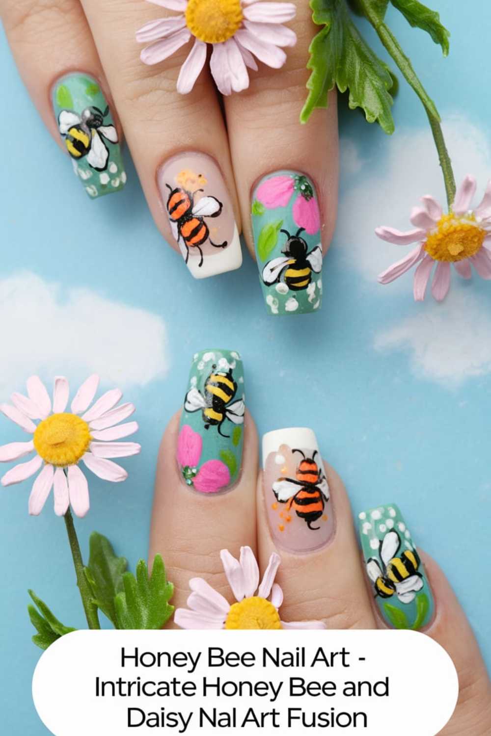 Close-up of bee nail art with intricate designs featuring honey bees and colorful flowers on a bright blue background. Daisies are placed around the nails, enhancing the summery theme.