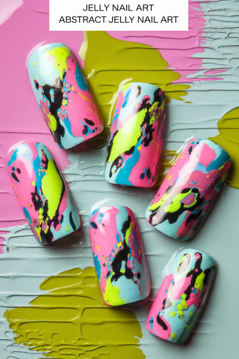Six artificial nails with abstract jelly nail art ideas feature splashes of vibrant pink, yellow, aqua, and black. The nails are set against a matching painted background, creating a colorful and dynamic visual effect.