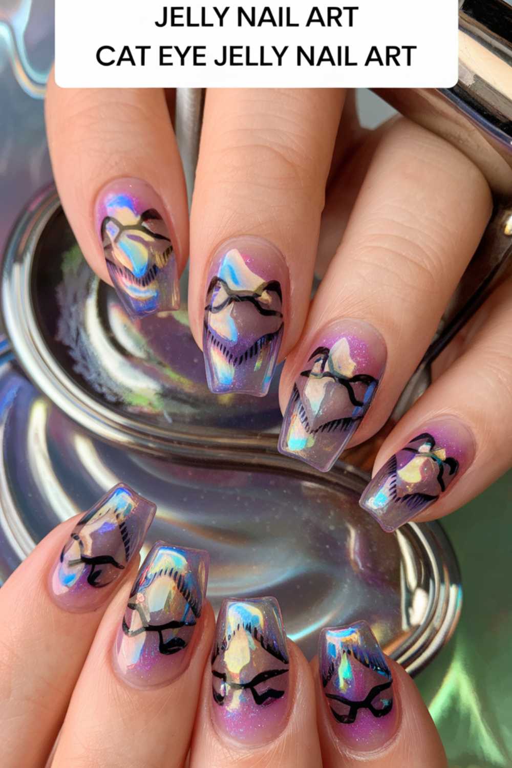 A set of hands displays stunning holographic jelly nail art with cat eye detailing, perfect for those seeking jelly nail art ideas. The nails boast a luminous, iridescent finish with stylized black designs that mimic cat eyes and intricate patterns.