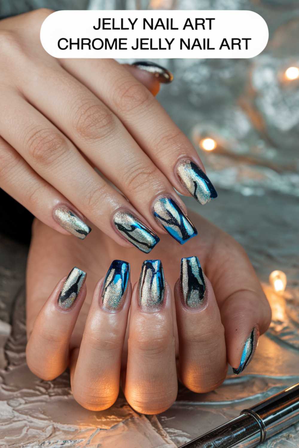 A person flaunts a manicure adorned with chrome jelly nail art in shimmering metallic silver and blue hues. The almond-shaped nails, accompanied by a decorative caption at the top, showcase stunning Jelly Nail Art Ideas for those seeking inspiration.