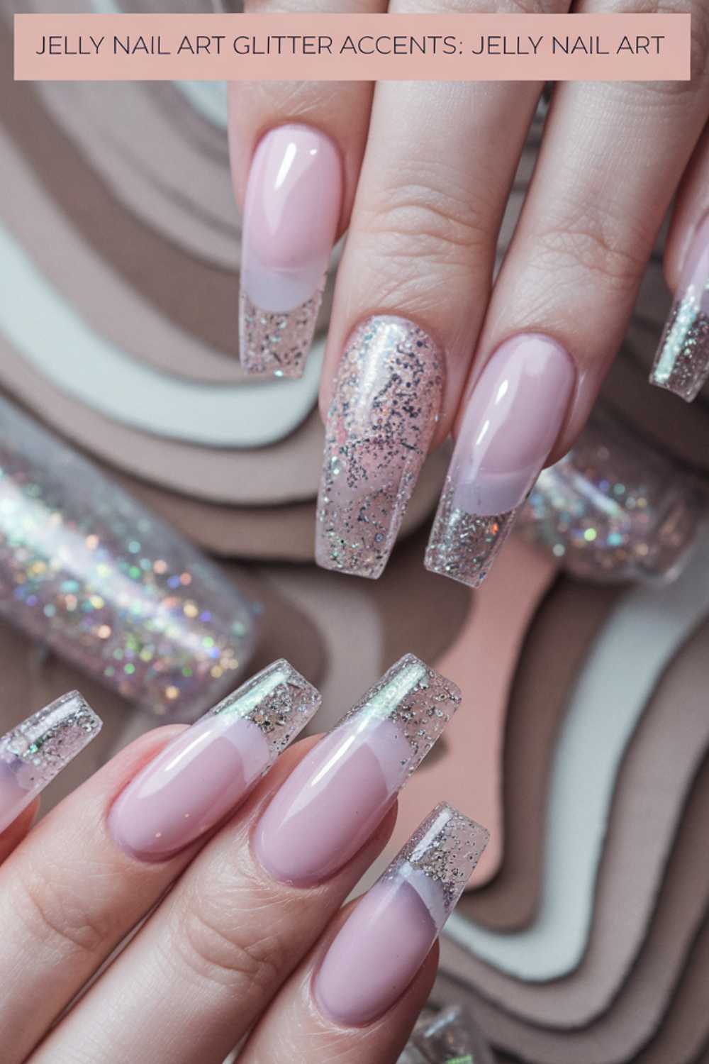 Close-up of hands showcasing stunning jelly nail art ideas. The nails boast clear tips with silver glitter accents for a sparkling effect, while a cylindrical glittery decoration shimmers in the background.