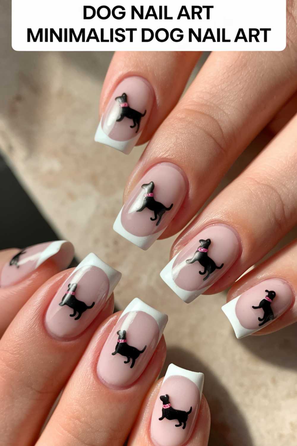 Close-up of hands featuring a minimalist dog nail art design. Each nail showcases a small black dog decal with a pink accessory on a nude base, elegantly finished with white French tips. Text above reads DOG NAIL ART MINIMALIST DOG NAIL ART.