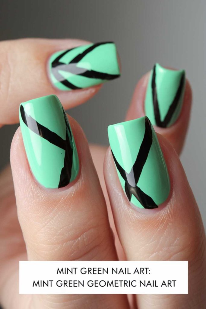Close-up of neatly manicured fingernails painted mint green, featuring bold black geometric lines in angular patterns. This modern and striking look perfectly showcases trendy green nail art.