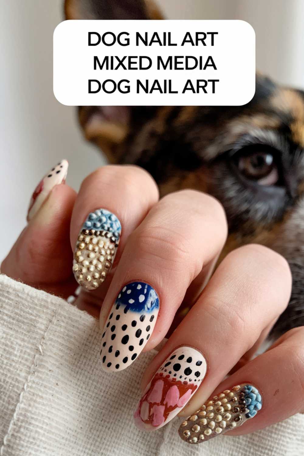 A close-up captures a hand adorned with dog-themed nail art, featuring a playful mix of polka dots, pearls, and vibrant designs. A dogs curious face peeks from the background. Above, a text box proudly displays: DOG NAIL ART MIXED MEDIA DOG NAIL ART.