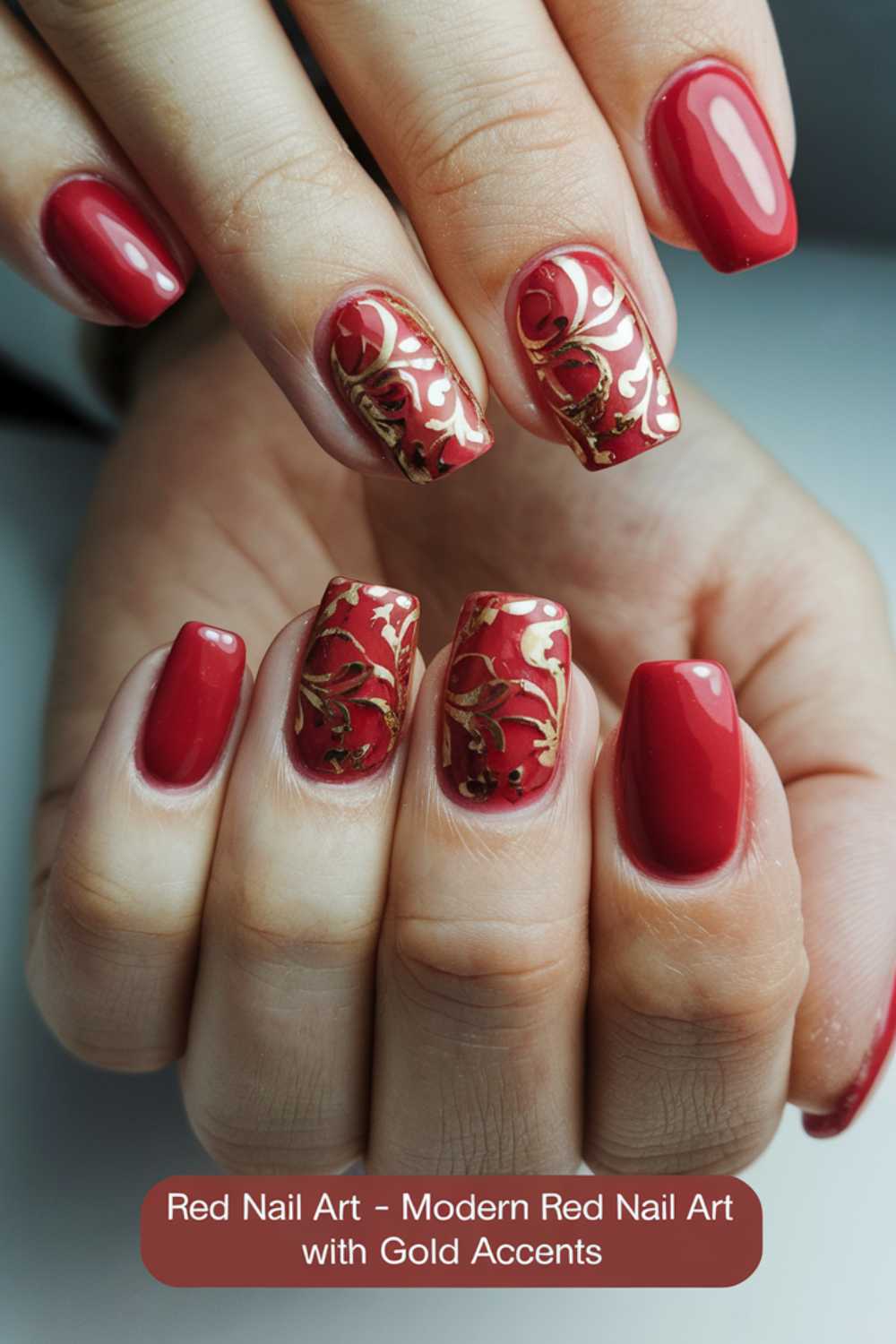 Close-up of hands with red nail art featuring gold floral accents. The design is on a few nails, while others are solid red. Nails are cleanly manicured, showcasing intricate patterns. Text at the bottom reads: Red Nail Art - Modern Red Nail Art with Gold Accents.