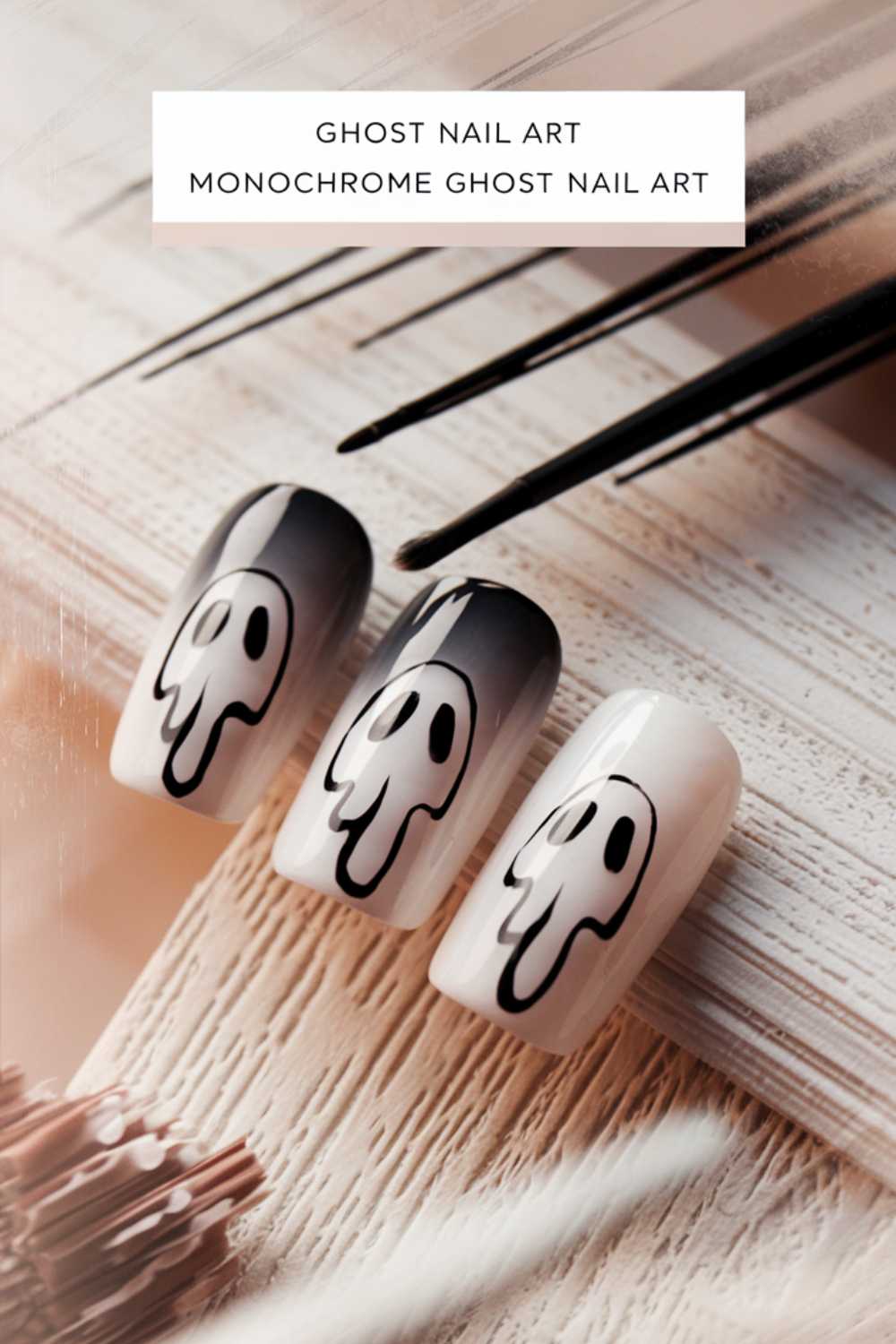 Close-up of three fingernails featuring monochrome ghost nail art. The nails display a blend of black and white shades with ghostly faces, set against a soft, blurred background with a text overlay reading Ghost Nail Art Monochrome Ghost Nail Art.