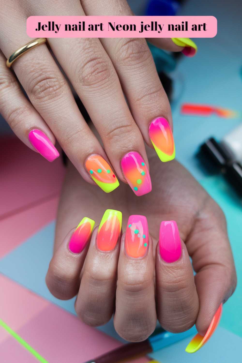 Close-up of hands showcasing vibrant neon jelly nail art in pink, orange, and yellow hues, with some nails adorned with turquoise dots. A pink label at the top reads, Jelly Nail Art Ideas: Neon jelly nail art.