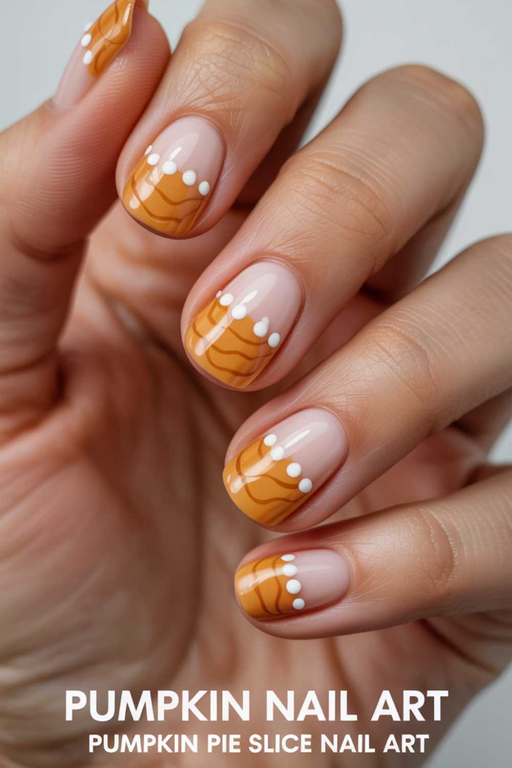 A hand with nails painted to resemble pumpkin pie slices, featuring orange tips with wavy lines and white dots along the edge. Text at the bottom reads: PUMPKIN NAIL ART PUMPKIN PIE SLICE NAIL ART.