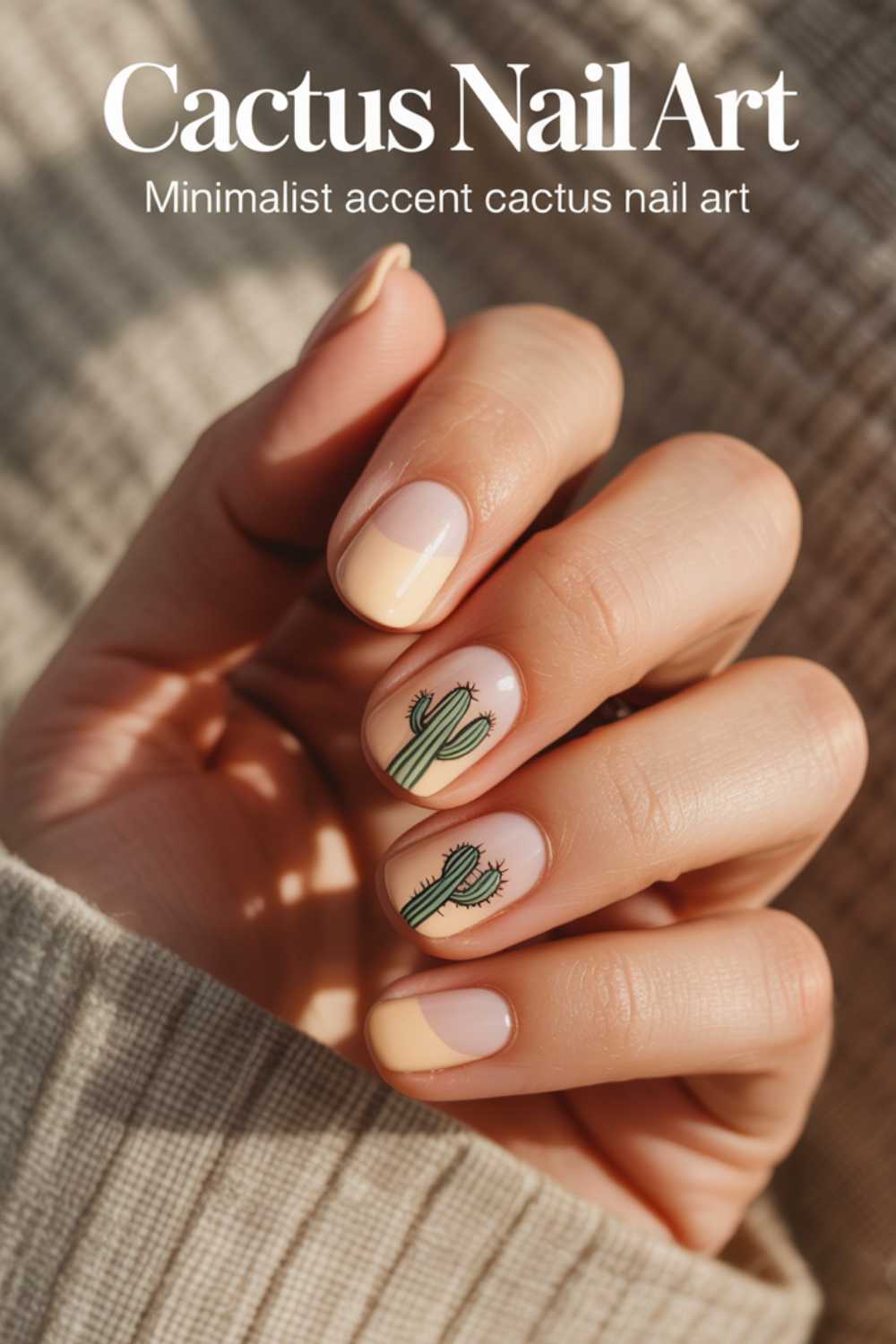 A hand with nude and beige minimalist nail art, featuring small green cactus designs on two fingernails. The person is wearing a beige sweater. Text reads: “Cactus Nail Art. Minimalist accent cactus nail art.”.
